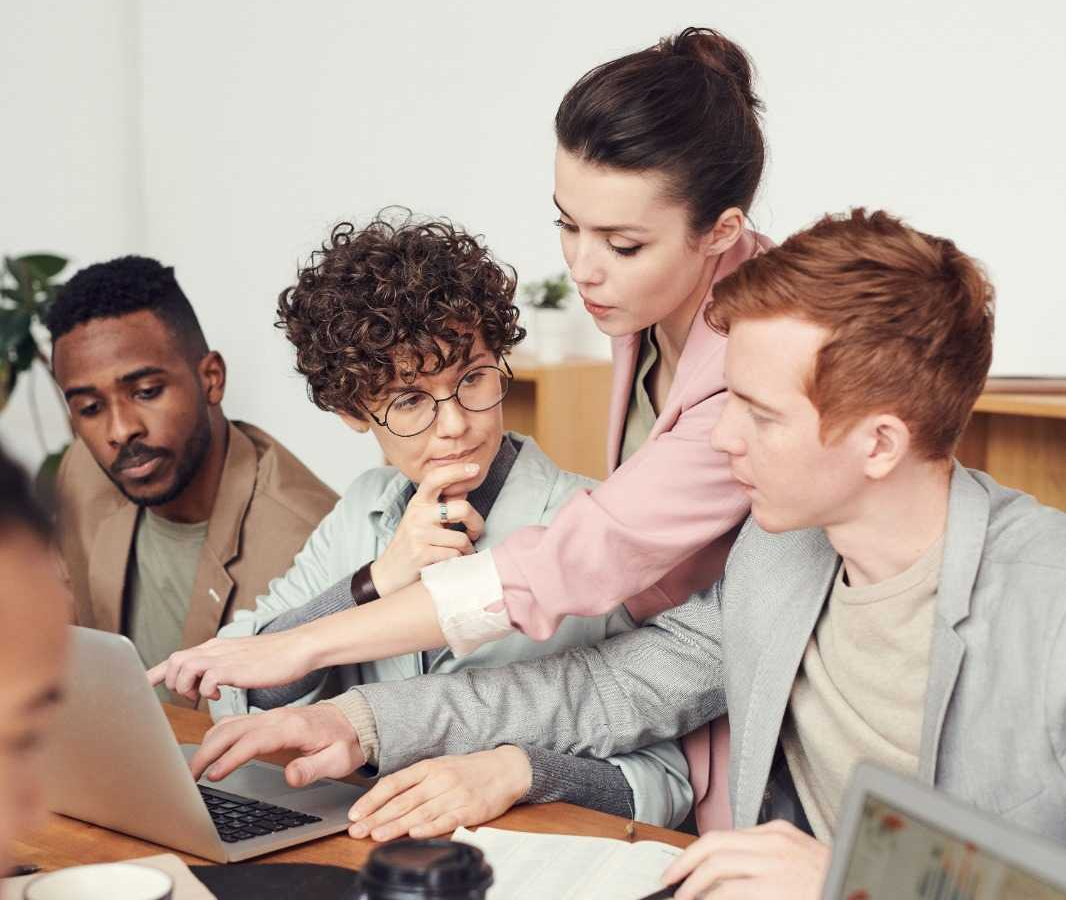 A colleague guiding a small group through information on a laptop.