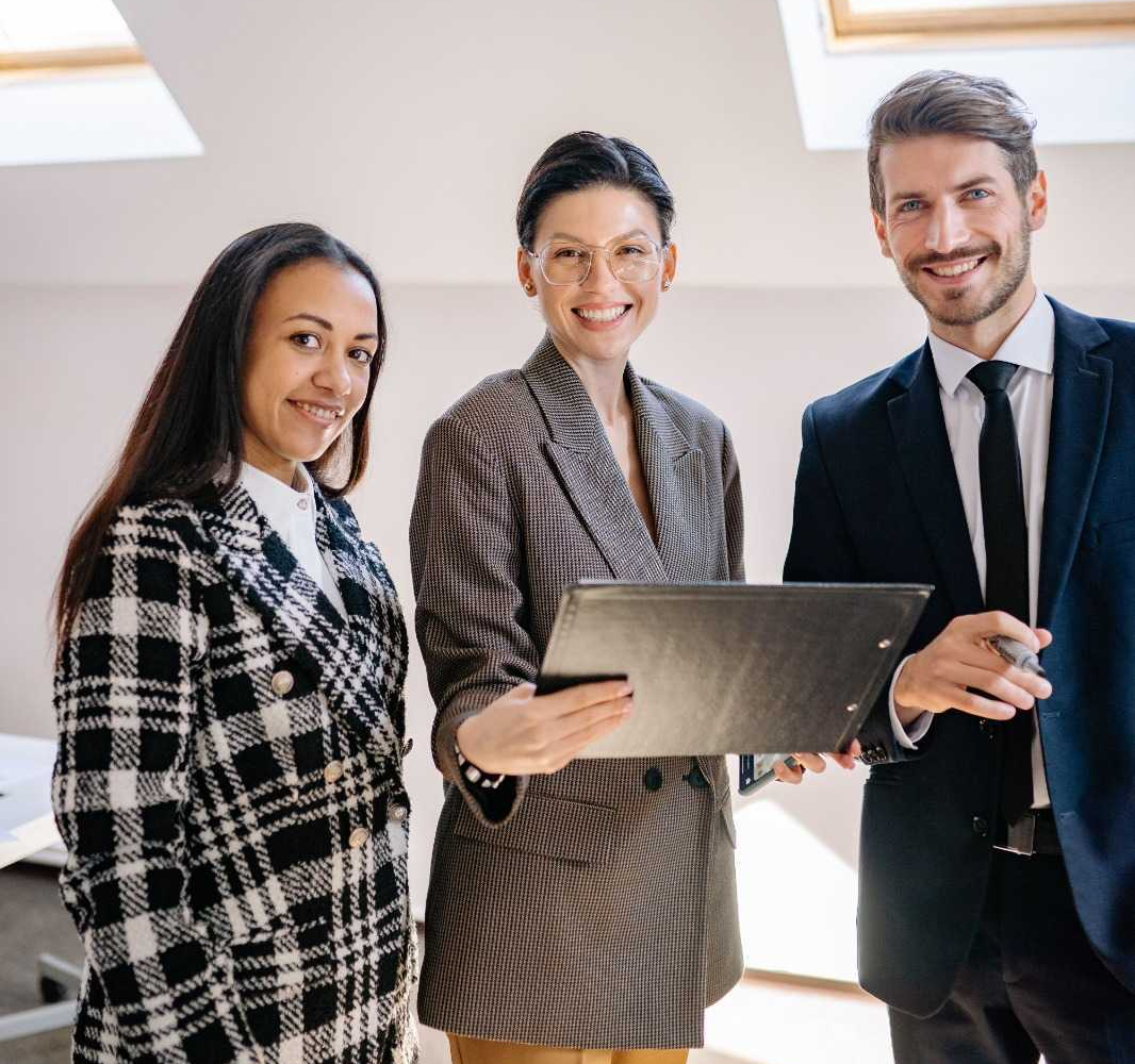 Three professionals standing together with a folder of documents.